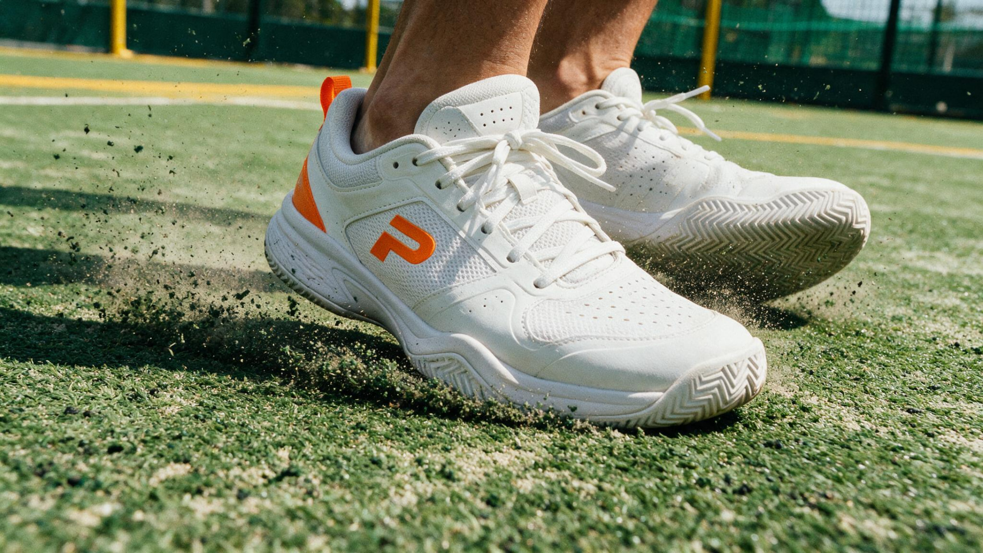 Close-up of white padel shoes pushing off the artificial turf court surface